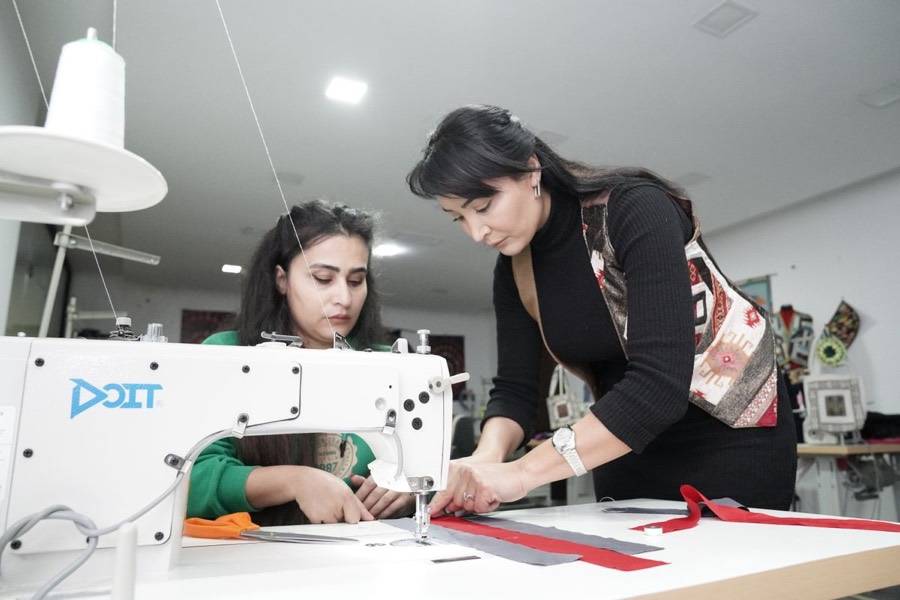Dos alumnas cosiendo juntas en el taller