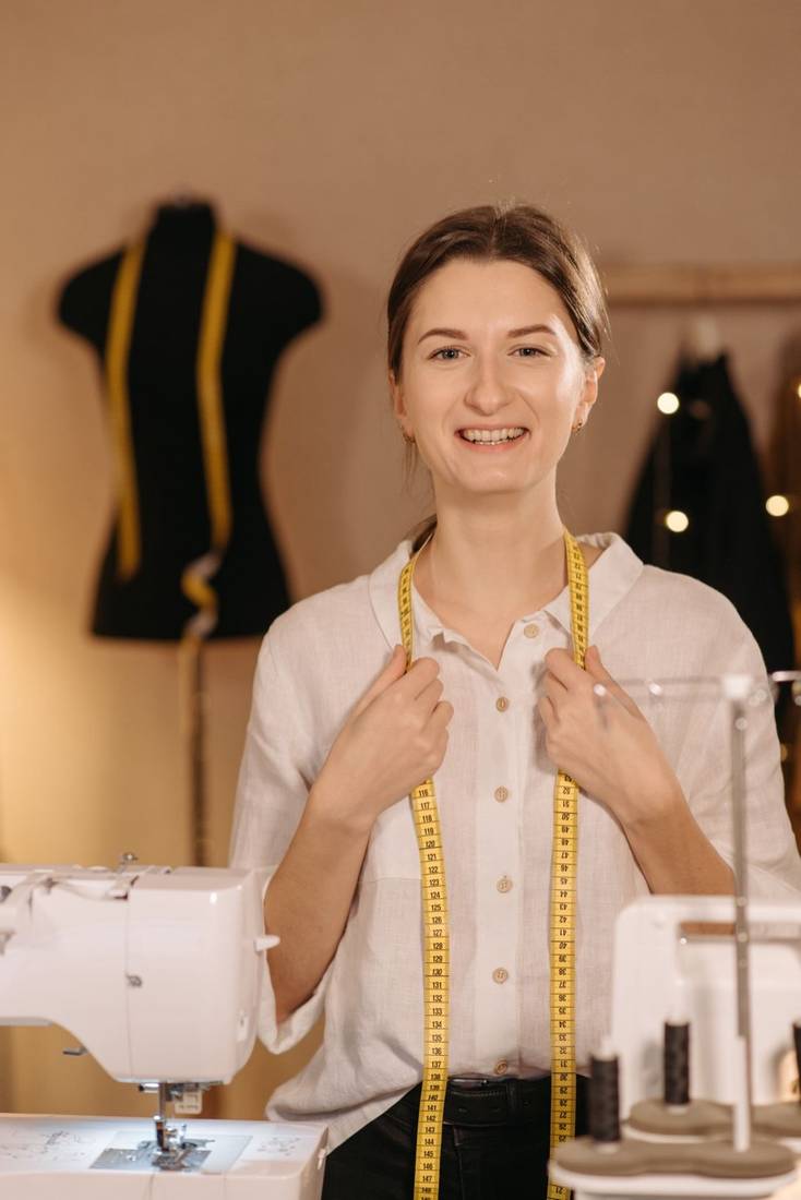 Costurera sonriente con una cinta métrica al cuello en su taller