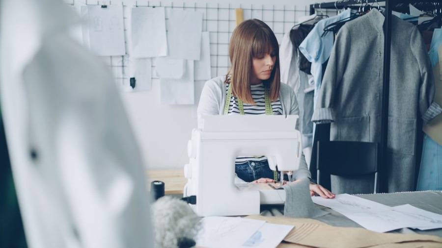 Diseñadora cosiendo en su estudio frente a la máquina