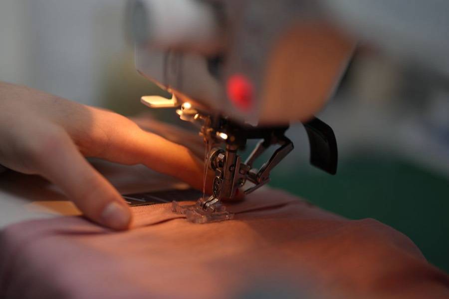 Mano guiando la tela bajo el pie de la máquina de coser