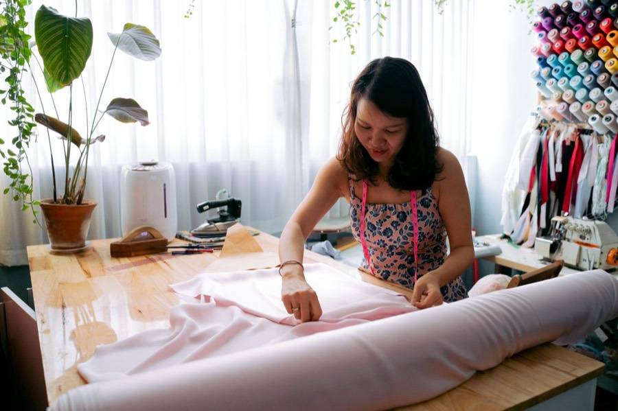 Costurera trabajando una tela rosada en un taller luminoso
